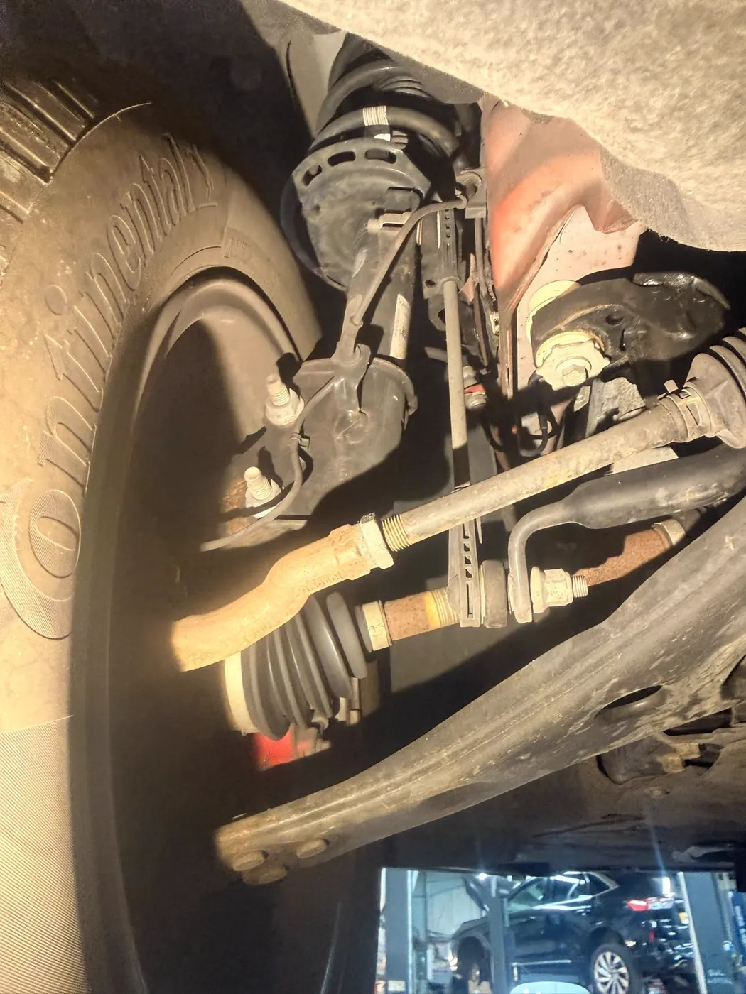 Front steering and suspension components viewed from underneath a car on a lift