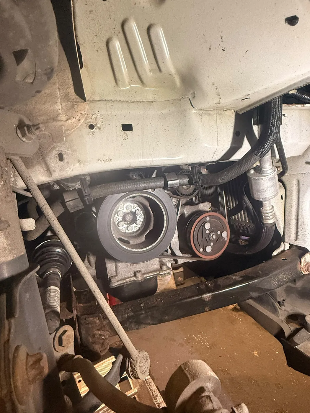Underside view of an engine and ancillary pulleys during a mechanical inspection